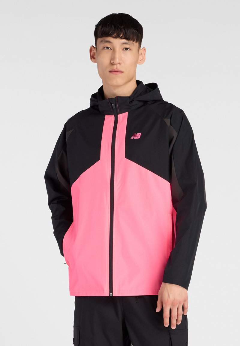 Giacca a vento leggera, nera e rosa brillante, con design geometrico, cerniera frontale e logo New Balance sul petto.