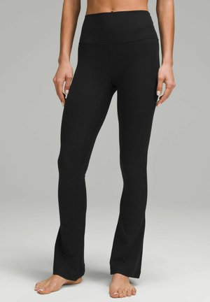 Černé zvonové legíny vyrobené z ribovaného materiálu s vysokým pasem, s hladkou texturou a obepnutým střihem.