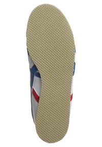 Suola in gomma beige con motivo di battistrada triangolare su scarpa sportiva, con parte superiore delle sneakers in bianco, blu e rosso visibile sui bordi.