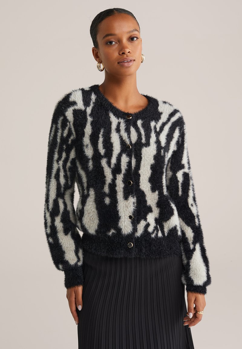Svartvit randig cardigan i en mjuk, fluffig textur. Har rund halsringning och knappstängning med guldfärgade detaljer.