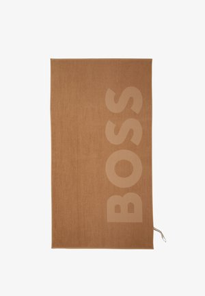 Serviette rectangulaire marron avec de grandes lettres verticales "BOSS" en relief sur le côté droit et une petite boucle rayée dans le coin inférieur.