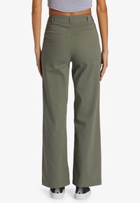 Olijfgroene wijde broek van een katoenmix, met een hoge taille, riemlussen en rechte pijpen, gecombineerd met casual sneakers.