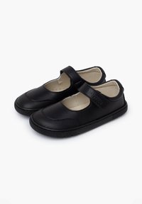 Zapatos Mary Jane de cuero negro con una tira de velcro, punta redondeada, acentos texturizados y suela de goma. El interior es de tela beige.