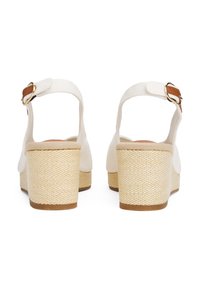 Hvite kilehælsandaler med en vevd beige jute hæl, canvasstropp og detalj med brun spenne, med en jevn tekstur på kroppen.