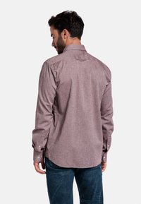 Langermig shirt in donkerrood met een subtiel patroon. Voorzien van een button-down kraag en manchetten met één knoop. Getailleerde pasvorm en een gebogen zoom.