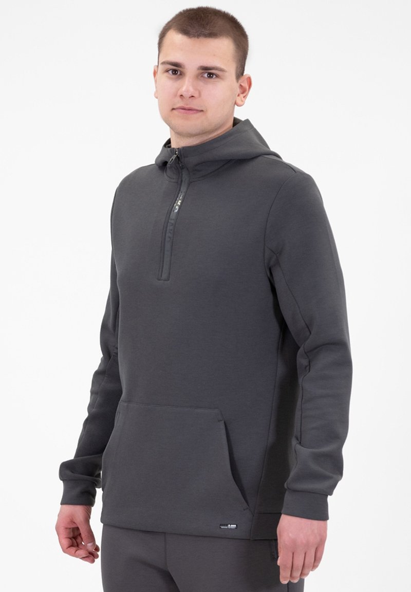 Felpa grigia con cappuccio in un materiale morbido, con zip a metà fronte, cappuccio foderato e tasca frontale. Presenta un etichetta del marchio discreta sull'orlo.