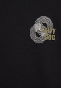 Melnas īsām piedurknēm T-krekls ar grafisku dizainu, kurā ir apļveida līnijas un uzraksts "SALTY DOG" olīvu zaļā krāsā. Izgatavots no kokvilnas materiāla.