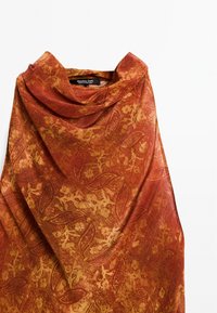 Tissu ambre drapé avec un motif floral et de feuilles subtil dans des nuances de rouge et d'or, présentant un design à col cowl ample.