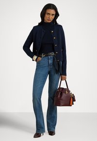 Tumši zils īss žakete ar zelta pogām, piegulošs melns augstu uzrullēts džemperis, gaiši zili izplesti džinsi un vīnsarkana somiņa ar bārkstīm.