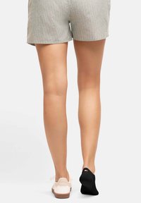 Randiga shorts kombinerade med en vit sko och en svart strumpa. Shortsen är av lätt tyg och har vertikala ränder i grått och vitt.