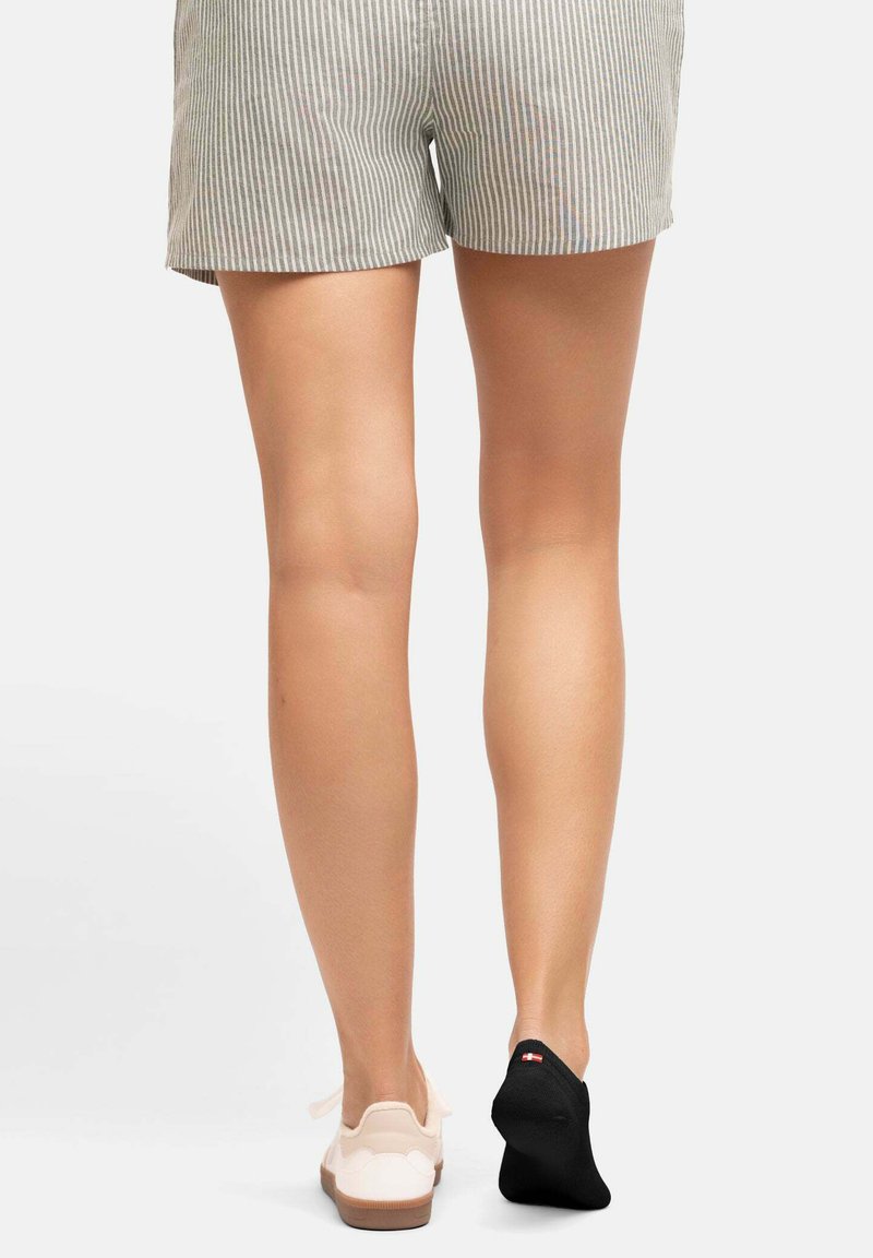 Gestreepte shorts in combinatie met een witte schoen en een zwarte sok. De shorts zijn van lichte stof en tonen verticale strepen in grijs en wit.