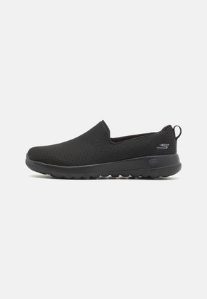 Zapatos negros sin cordones con un upper de malla transpirable, suela acolchada y patrones texturizados para agarre y soporte. Diseño ligero.