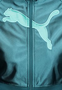 Τζάκετ από ύφα σμα σε τιρκουάζ χρώμα με κεντρικό φερμουάρ και μεγάλο κεντημένο λογότυπο Puma με μια γάτα που πηδάει στο ύψος του στήθους.