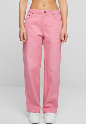 Roze cargo-broek van denim met een losse pasvorm. Voorzien van zijzakken, riemlussen en metalen sluitingen. Gepaard met witte schoenen.