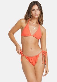 Set bikini rigato corallo, con top a triangolo con spalline regolabili e slip laterali con lacci, realizzato in morbido tessuto testurizzato.