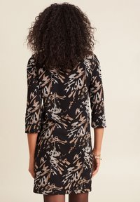 Schwarzes Kleid mit dreiviertellangen Ärmeln, das ein auffälliges, abstrahiertes Muster in Beige und Grau zeigt. Glatte Stoffqualität mit figurbetontem Schnitt.