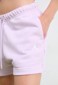 Light purple athletic shorts with an elastic waistband, side pockets, and a white Jordan logo stitched on the left leg. Smooth fabric texture.