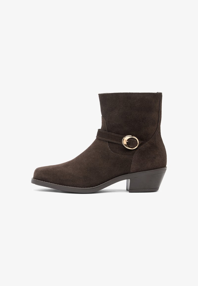 Bottine en daim marron foncé avec petit talon bloc et sangle décorative avec boucle ronde dorée sur le côté.