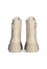 Beige enkellaarzen met een glanzende afwerking, voorzien van zijritsen en een chunky zool. G accented met een logo detail op de hak.