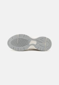 Schuhsohle mit grauem und weißem Gummi-Profil, das hexagonale Muster, Rillen und ein "SOFTFOAM"-Label im Bogenbereich aufweist.