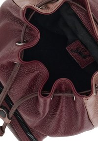 Borsa a secchiello in pelle bordeaux con finitura testurizzata, chiusura con coulisse e rivestimento in tessuto scuro. Include un'etichetta del marchio all'interno.