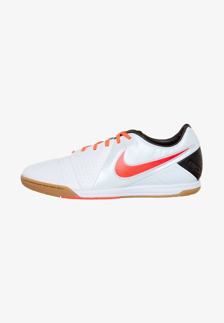 Chaussure de sport blanche avec des accents orange, surface texturée, talon noir et semelle en caoutchouc naturel. Présente un logo Nike bien visible sur le côté.