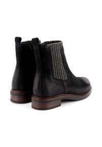 Stivali alla caviglia in pelle nera con finitura texture, pannelli laterali elasticizzati e tacco in legno impilato. Cuciture grigie in evidenza sui pannelli elasticizzati.