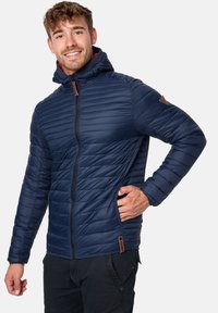 Navy padded jacket with a hood, zip front, sideways pockets, and textured quilted design. Features leather-like logo patch on the shoulder.