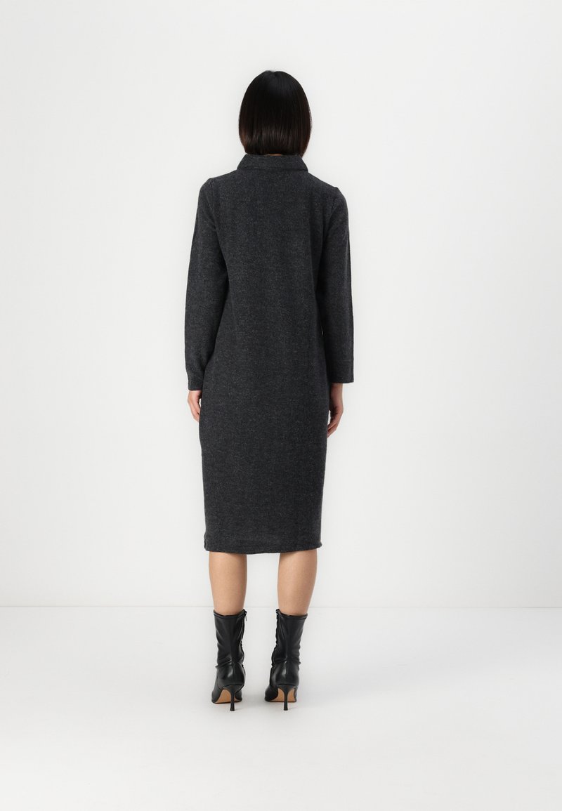 Robe en laine gris charbon avec une longueur mi-mollet, des manches longues et un col. Texture lisse, silhouette ajustée et détails subtils à l'ourlet.