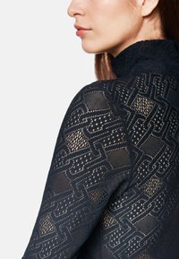 Schwarzes Spitzentop mit aufwendigen Ausschnittmustern und hohem Kragen. Der Stoff hat eine transparente Textur mit einem schichtigen Aussehen.