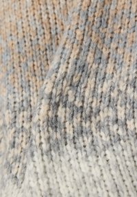 Gestrickter Stoff mit Creme-, Beige- und Grautönen, verschiedenen Texturen und einem weichen, wollähnlichen Aussehen. Definiert ein leicht geripptes Muster.