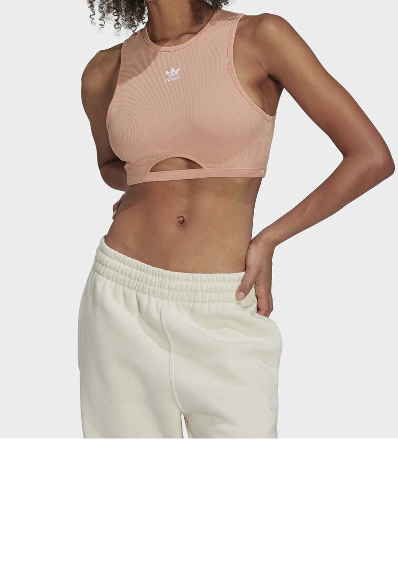 Różowy ribbed crop top z okrągłym dekoltem i wycięciem, zestawiony z off-white dresami na elastycznej talii. Klasyczne logo Adidas.