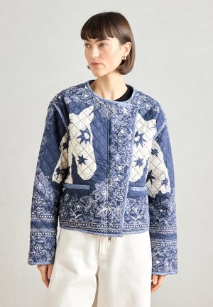 Quiltet jakke i mørkeblå med hvide blomstermønstre og dyremotiver. Har en rund halsudskæring og manchetter, afsluttet med en lys trim.