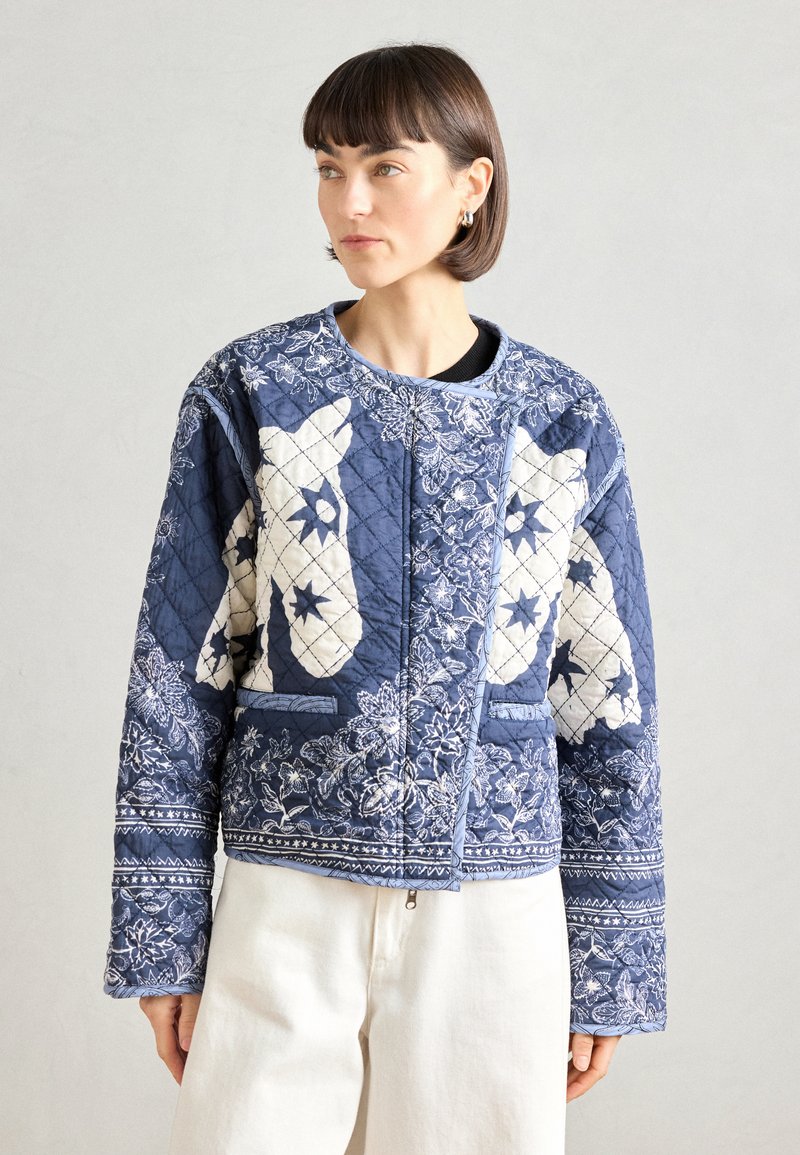 Κουβερτο jacket σε σκούρο μπλε χρώμα με λευκά λουλουδάτα μοτίβα και ζωϊκά σχέδια. Διαθέτει στρογγυλή λαιμόκοψη και μανίκια, τελειωμένο με μια ελαφριά επένδυση.