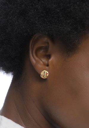 Goldstudohrringe mit einem kreisförmigen Design, das farbige Steine, einschließlich roter und klarer Akzente, auf einer strukturierten Oberfläche zeigt.