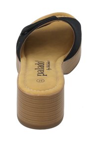 Sandale à semelle noire avec une semelle extérieure texturée et un coussinet de couleur beige, présentant une seule sangle sur le dessus et un talon compensé.