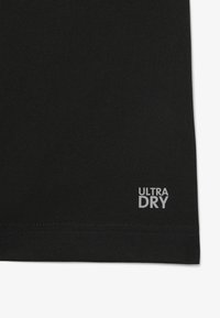 Tessuto nero con superficie strutturata, caratterizzato da un piccolo logo "ULTRA DRY" in bianco nell'angolo inferiore. Design rettangolare semplice.