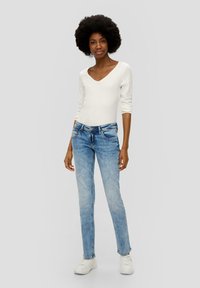 Lichtblauwe denim jeans met een slim fit, vijf-pocket ontwerp en een vervaagde afwerking, gecombineerd met een witte, aansluitende, lange mouw V-hals top.