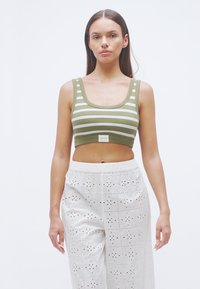 Πράσινο και λευκό τοπ με ρίγες, υφή ριμπ και φαρδιές τιράντες, συνδυασμένο με λευκό, φαρδύ παντελόνι με σχέδιο οπής.