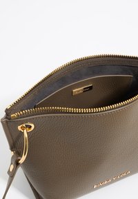 Olive green leather pouch bag with gold hardware, zip closure, and embossed brand logo inside. Textured surface and smooth lining.