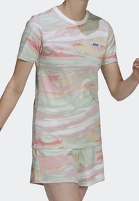 Sada trička s krátkým rukávem a šortkami v pastelových barvách se zvlněným vzorem. Vyrobeno z lehkého materiálu s kulatým bílým výstřihem.