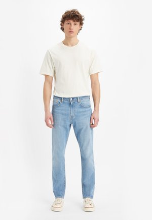 Lightweight beige t-shirt and light blue straight-leg jeans. Features a classic design with subtle stitching and standard hardware accents.