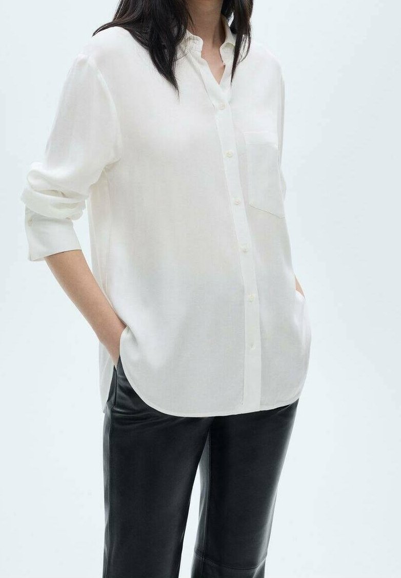 Witte button-up overhemd van lichtgewicht stof, met een borstzak, oprolbare mouwen en een gebogen zoom. Gepaard met zwarte leren broek.