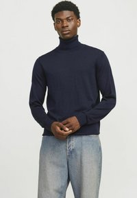 Mornarski pulover s turtleneck ovratnikom, izdelan iz mehkega pletenega materiala, z dolgimi rokavi, prilegajočim ovratnikom in subtilnimi rebrastimi detajli na rokavih in robu.