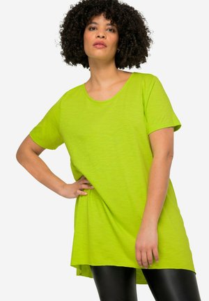 Limegrünes, übergroßes T-Shirt aus leichtem, strukturiertem Stoff mit rundem Halsausschnitt und kurzen Ärmeln, kombiniert mit schwarzen Leggings.