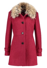 Punainen villakangastakki, jossa on tekoturkistsolka, kolme mustaa nappia ja istuva vyötärö. Takissa on pitkät hihat ja sivutaskut.