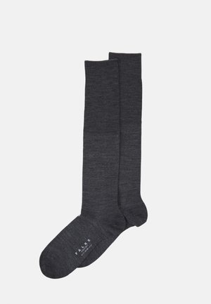 Dunkelgraue, knielange Socken aus einem weichen, strukturierten Material. Sie verfügen über eine verstärkte Ferse und Zehen, mit einem auf der Sohle aufgedruckten Logo.