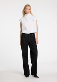 Top bianco a collo alto e maniche corte con un sottile accento argento, abbinato a pantaloni neri a gamba larga a vita alta.