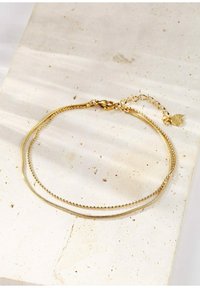 Pulsera de oro que presenta dos cadenas superpuestas: una lisa y otra de cuentas, con un cierre de langosta y una cadena de extensión para ajustar la longitud.
