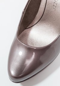 Gros plan sur l'avant pointu mauve métallique brillant d'une chaussure plate pour femme avec une semelle intérieure argentée texturée.